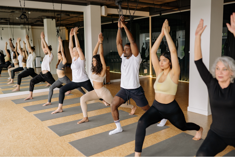 Physical Rest Image. Image is of a yoga class that has 7 adults with different ages and racial backgrounds participating in a group yoga class.