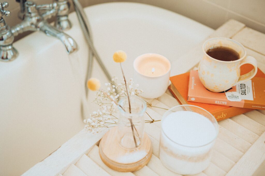 Navigating the Holidays with Chronic Illness self care image. Depicts a bath with a candle, book, and cup of tea.