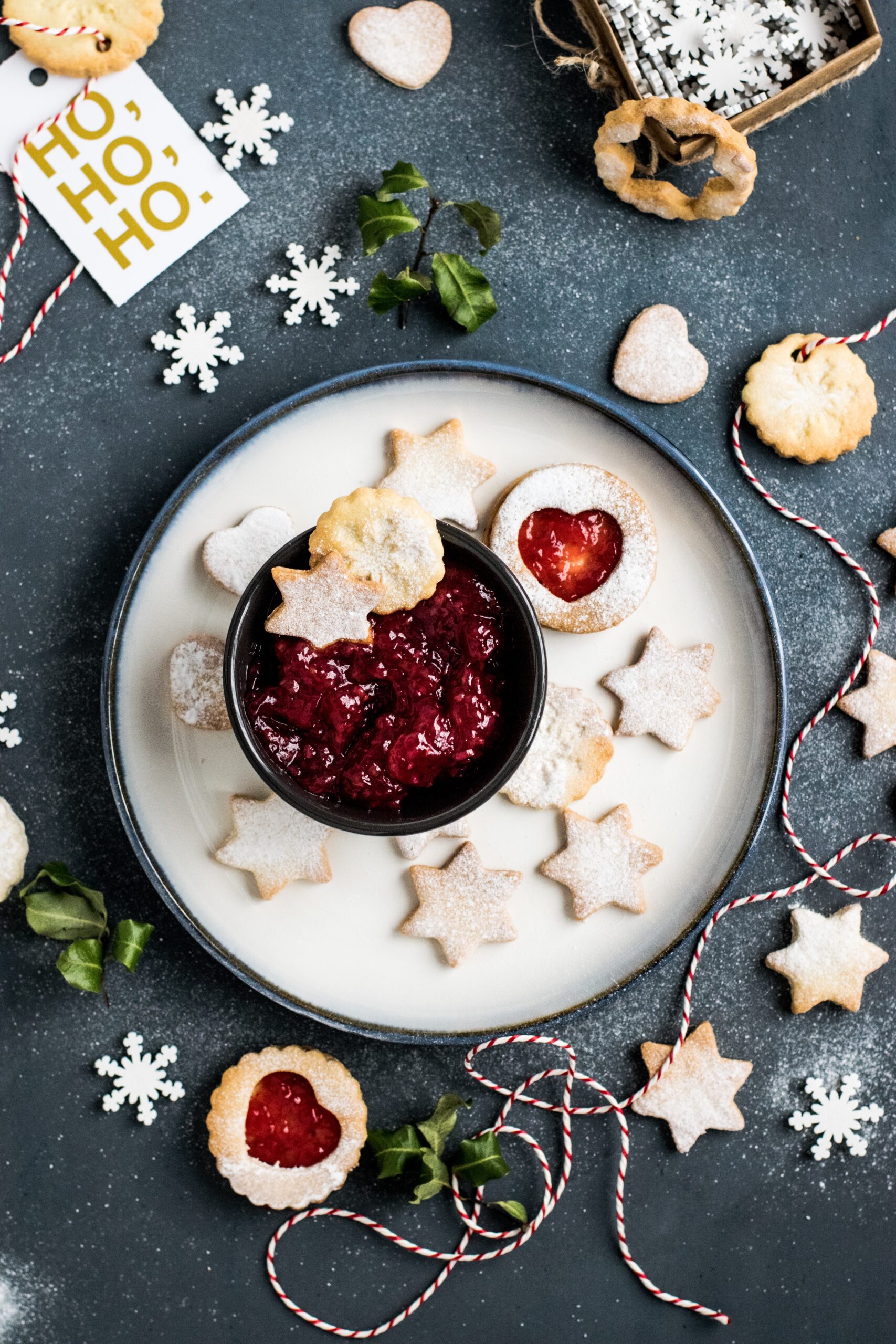 Arial view of a white plate with cookies and red dip. There are festive holiday decorations all around the plate of cookies.